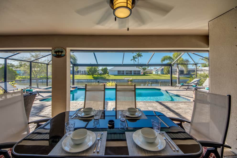 Outdoor dining table overlooking pool and canal